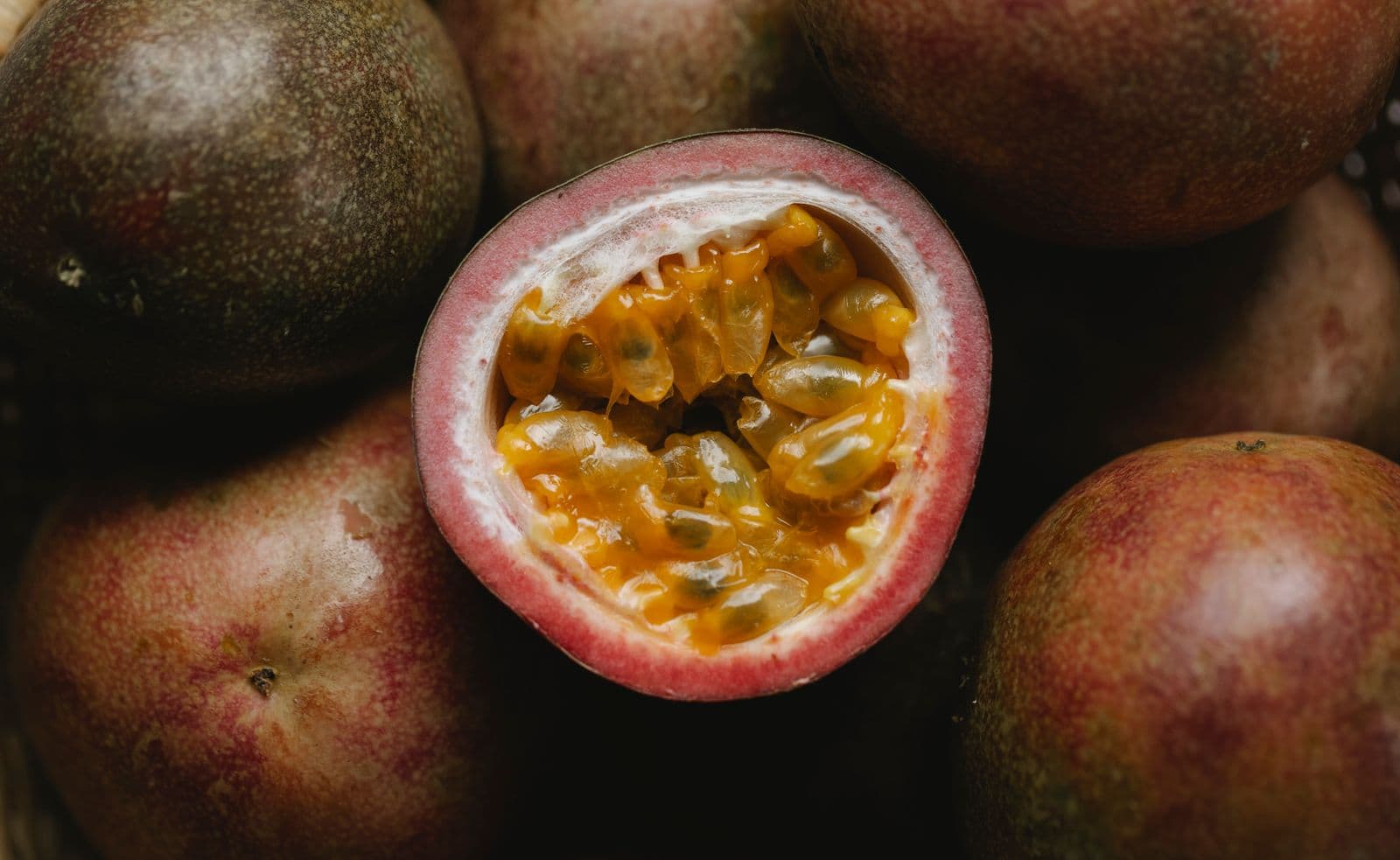 A ripe passion fruit cut in half, revealing its juicy golden-orange pulp