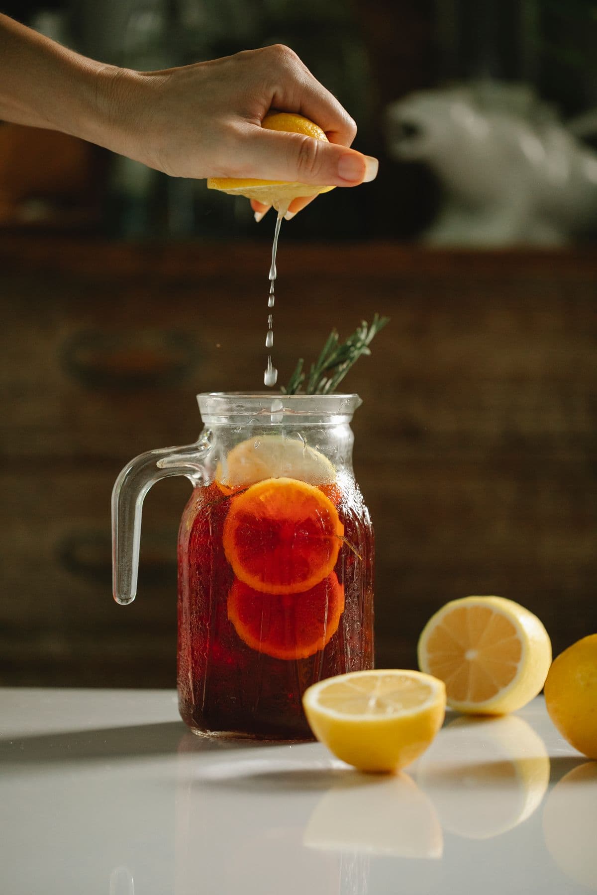 Squeezing citrus into a batch pitcher of fruit drink for a party