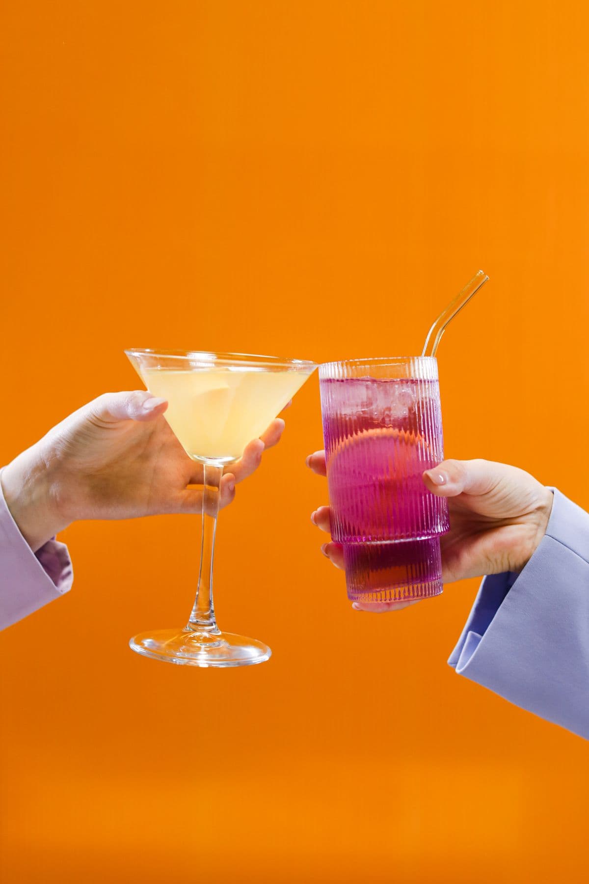 Hai ly cocktail chạm nhau trên nền sắc cam ấm, không nhãn chai