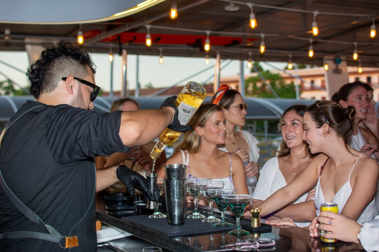 Bartender pha chế tại quầy bar di động ngoài trời trên boong, phục vụ nhóm khách dự tiệc lúc hoàng hôn