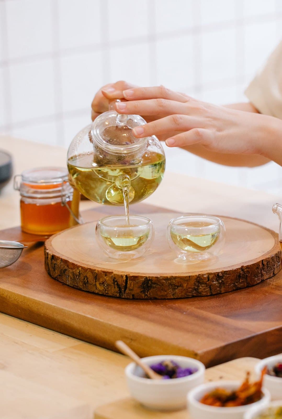 Rót trà từ ấm thủy tinh ra chén; màu nước trà phản ánh độ khoáng của nước dùng pha