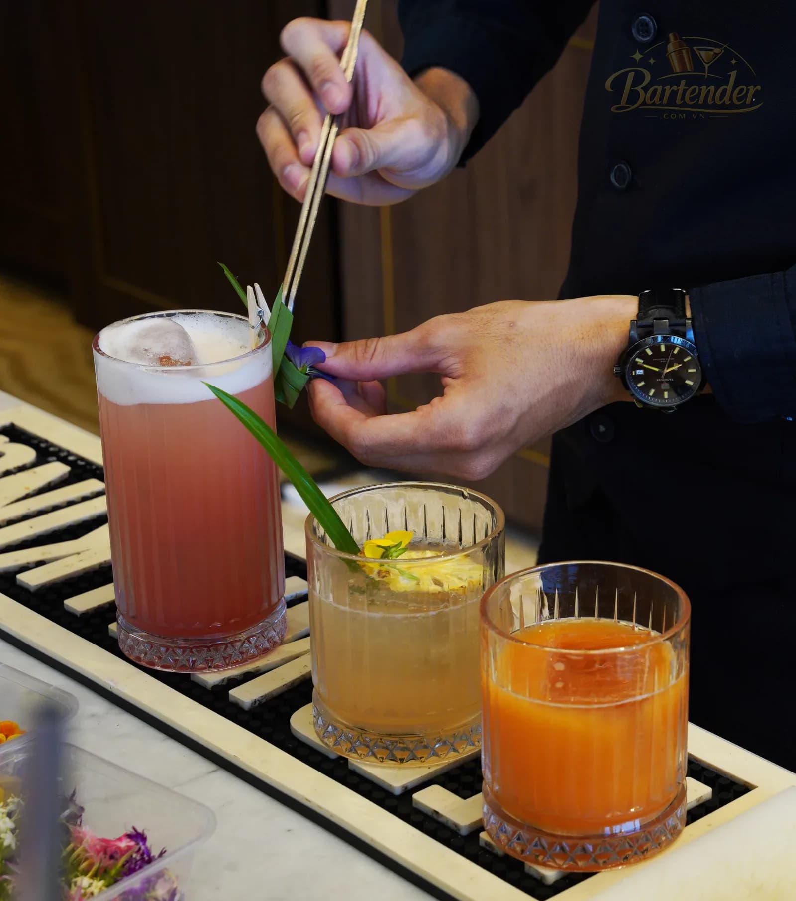 Bartender trang trí hoa ăn được lên ly thức uống hoàn thiện
