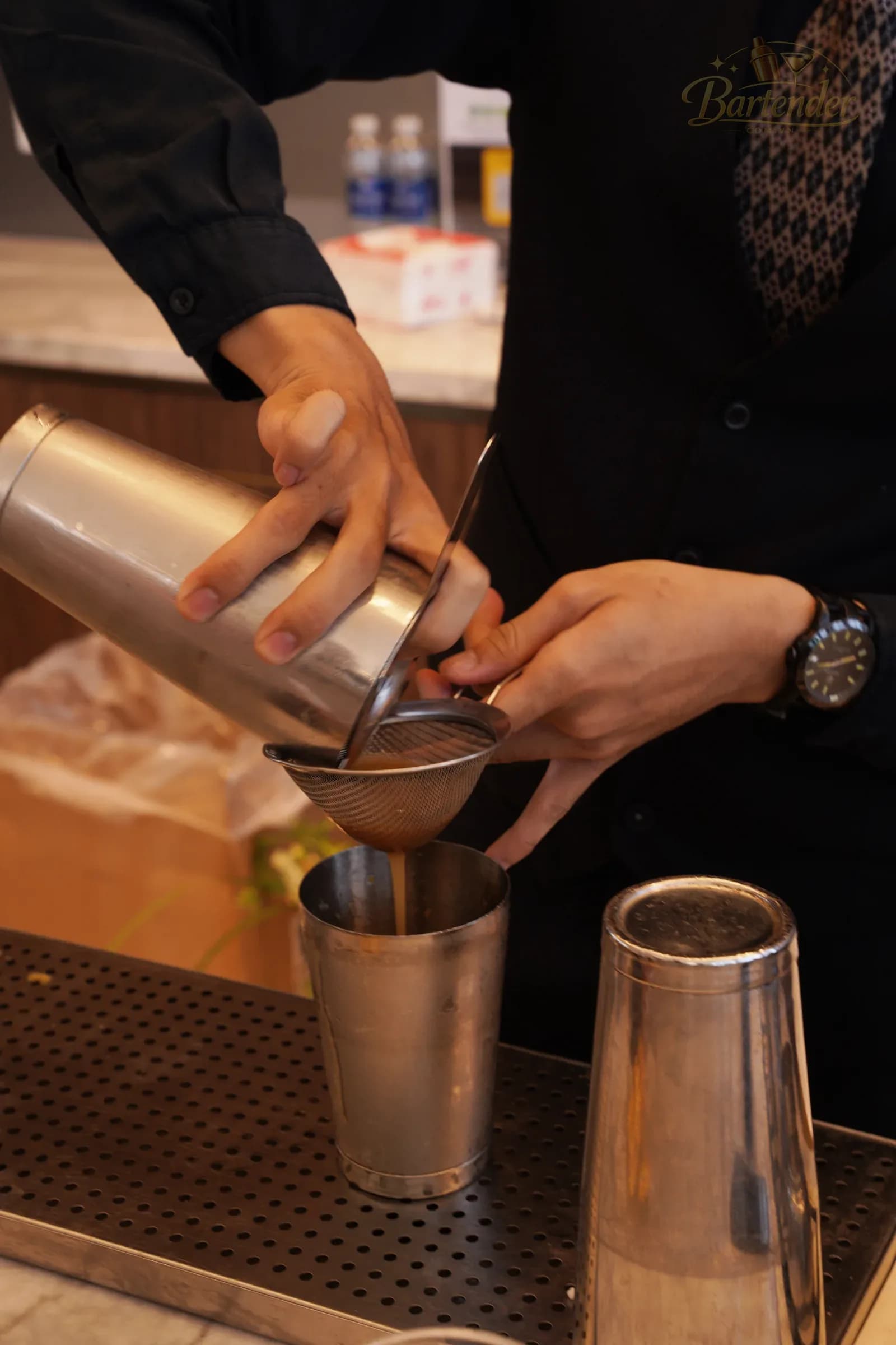 Bartender lọc thức uống qua rây tại quầy phục vụ trong sự kiện