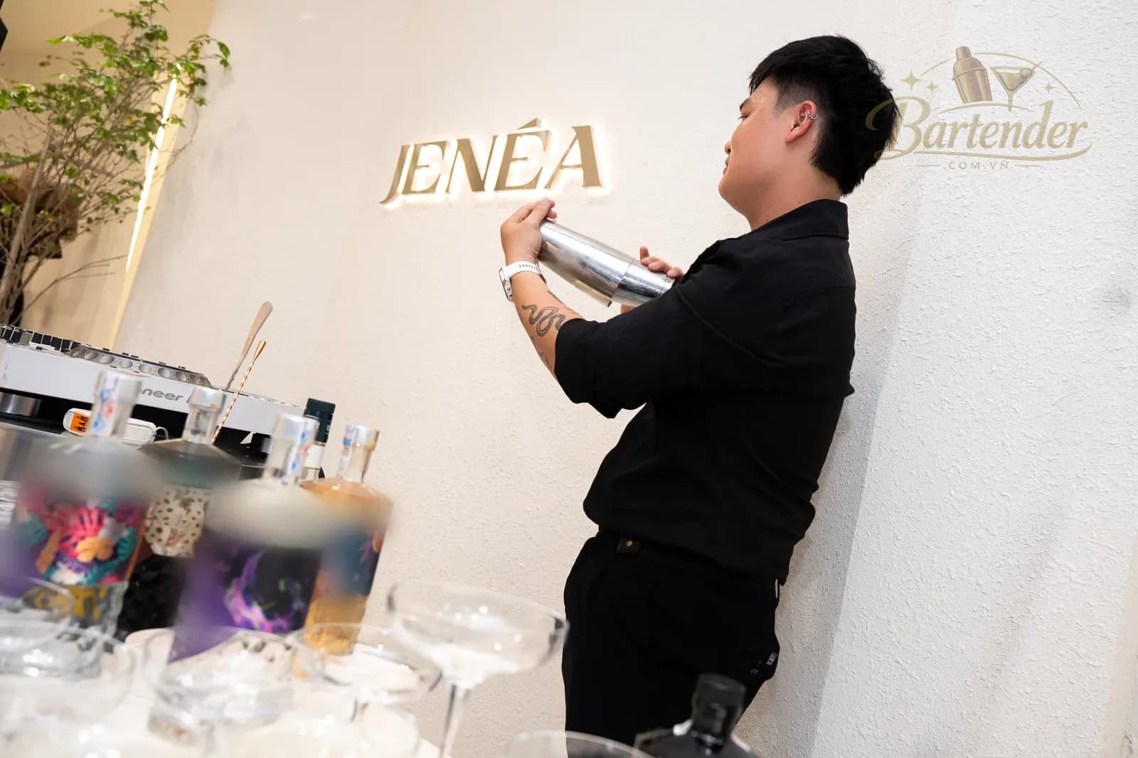 Bartender lắc shaker dưới bảng hiệu Jenéa